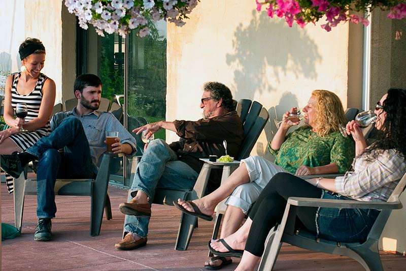 Guests enjoying wine while sitting in adironack chairs.
